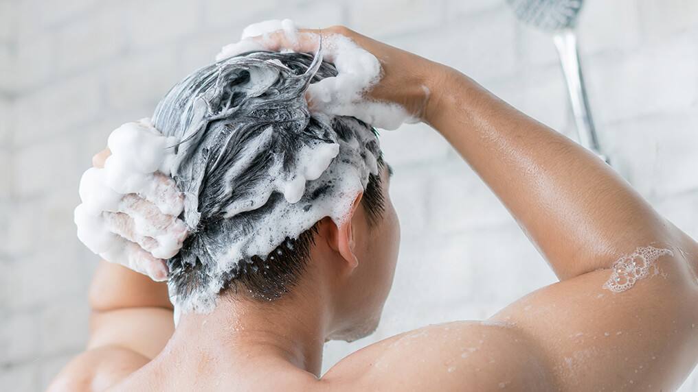 Homem de costas lavando os cabelos durante o banho